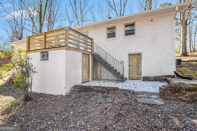 rear view of property featuring brick siding and stairs