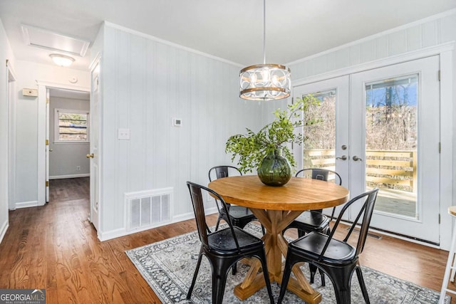 dining space with wood finished floors, visible vents, french doors, attic access, and crown molding