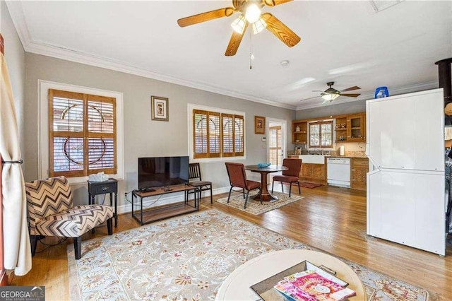 living area with crown molding, baseboards, and wood finished floors