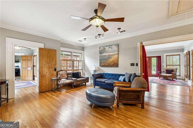 living room featuring ceiling fan, light wood-style floors, a wealth of natural light, and ornamental molding