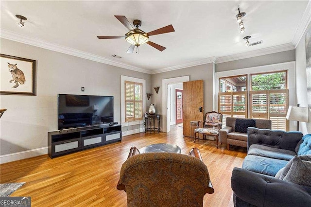 living room with light wood finished floors, visible vents, crown molding, ceiling fan, and baseboards