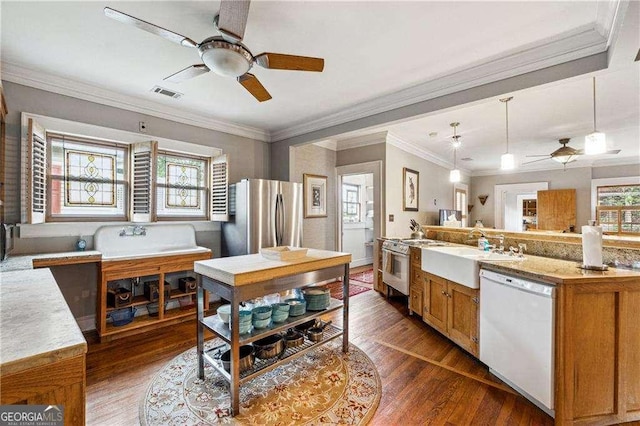 kitchen featuring wood finished floors, brown cabinetry, freestanding refrigerator, a sink, and dishwasher