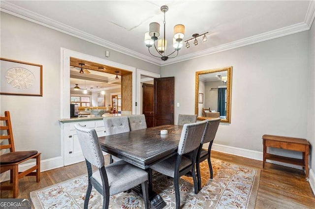 dining space featuring crown molding, a notable chandelier, wood finished floors, and baseboards