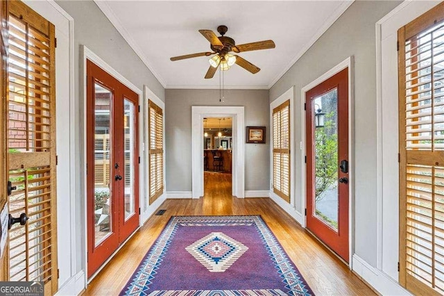 doorway to outside with crown molding, baseboards, french doors, wood finished floors, and a ceiling fan