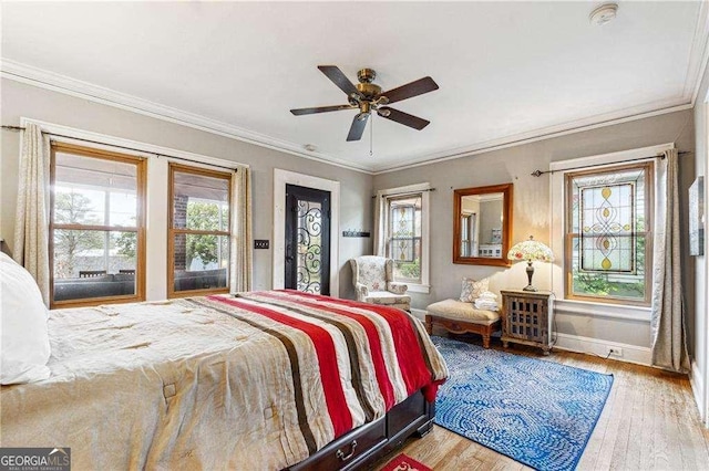 bedroom featuring ceiling fan, baseboards, wood finished floors, and ornamental molding