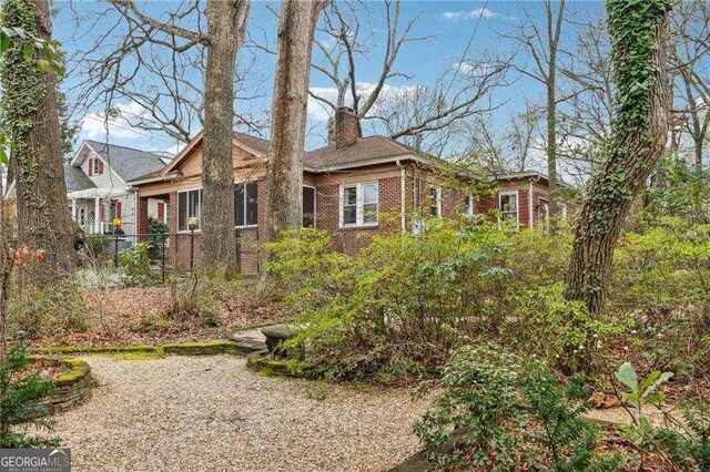 exterior space with fence, brick siding, and a chimney