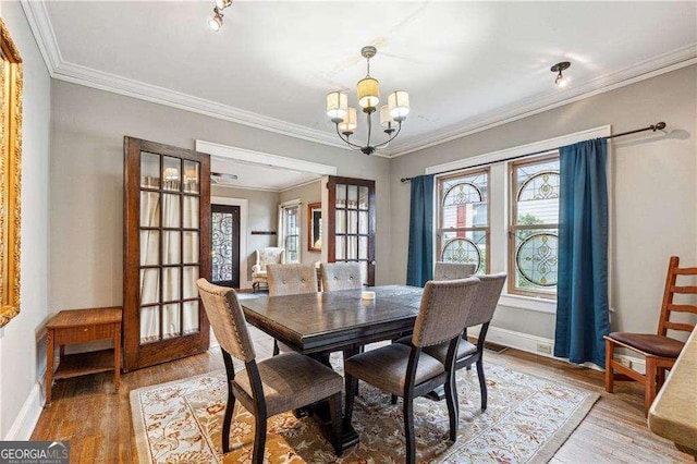 dining area with light wood-style flooring, ornamental molding, french doors, baseboards, and a chandelier