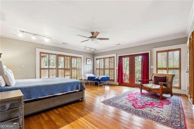 bedroom featuring access to exterior, crown molding, multiple windows, and wood finished floors