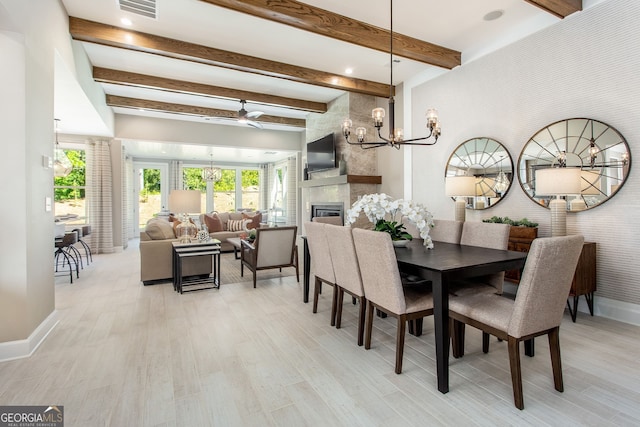 dining room with a fireplace, visible vents, light wood-type flooring, beamed ceiling, and baseboards