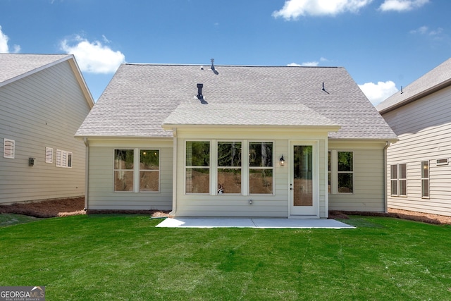 back of house featuring a shingled roof, a lawn, and a patio area