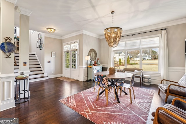 dining area featuring a notable chandelier, wainscoting, wood finished floors, and crown molding