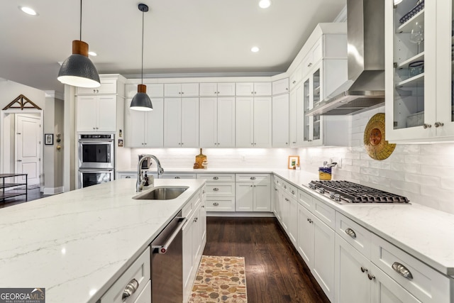 kitchen featuring dark wood-type flooring, wall chimney exhaust hood, white cabinets, and a sink