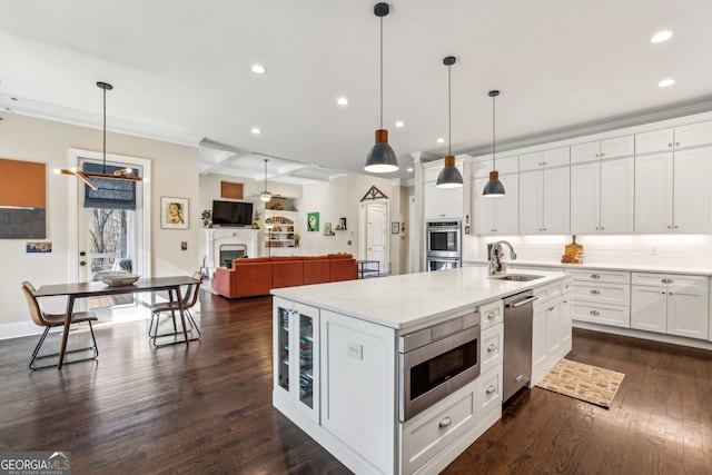 kitchen with a fireplace, decorative backsplash, appliances with stainless steel finishes, dark wood-type flooring, and a sink