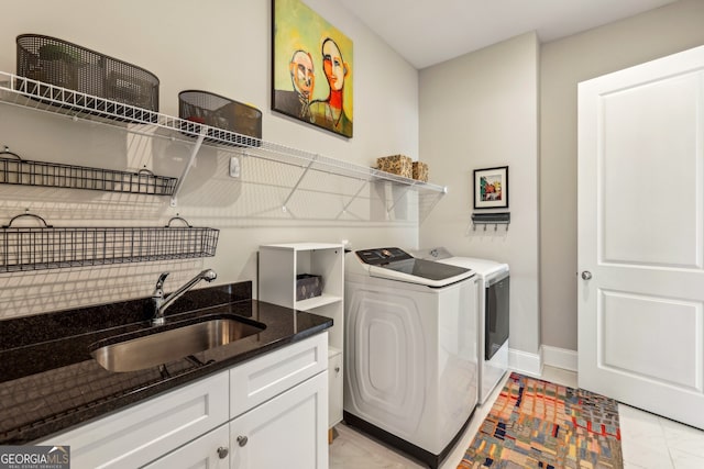 clothes washing area with independent washer and dryer, cabinet space, a sink, and baseboards