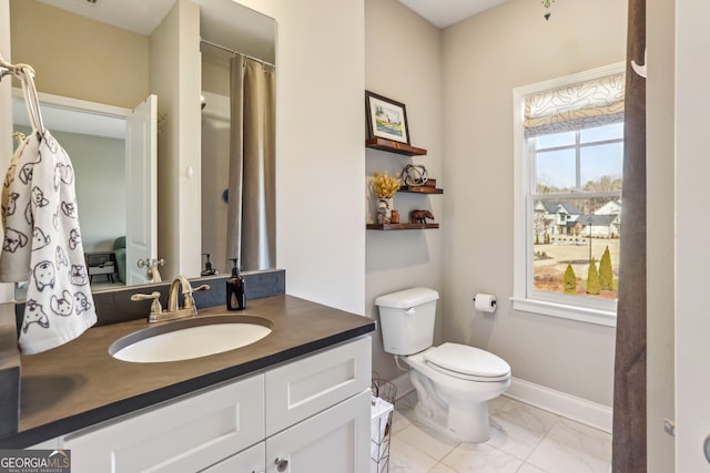 bathroom featuring toilet, marble finish floor, baseboards, and vanity