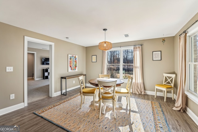 dining room featuring a healthy amount of sunlight, wood finished floors, visible vents, and baseboards