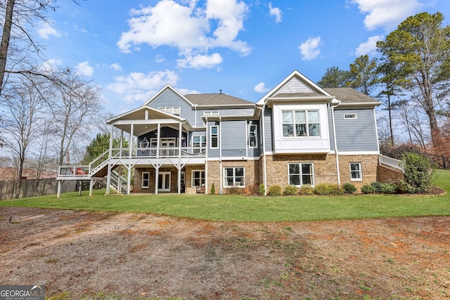 rear view of house with stairway, a deck, a lawn, and brick siding