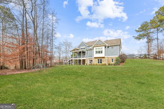 view of front of house with stairs, stone siding, a front yard, and fence