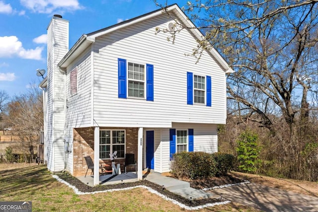 view of front of home with a chimney and brick siding