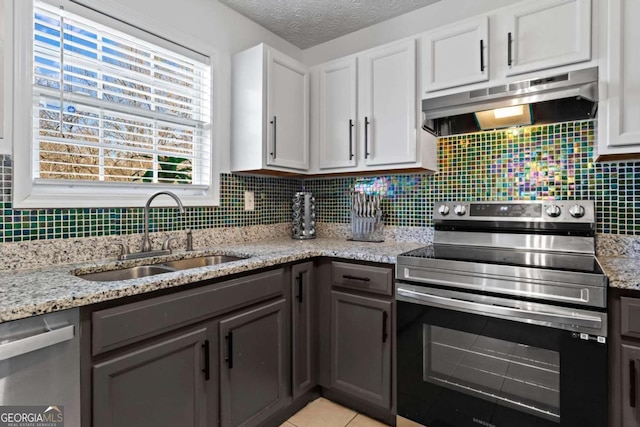 kitchen featuring backsplash, appliances with stainless steel finishes, a sink, a textured ceiling, and under cabinet range hood