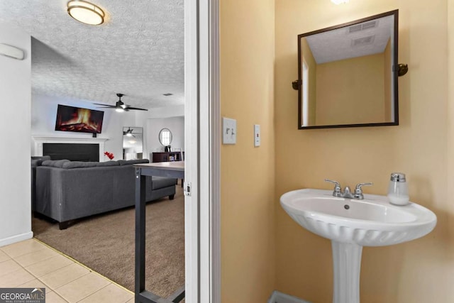 bathroom featuring a textured ceiling, ceiling fan, tile patterned flooring, a fireplace, and visible vents