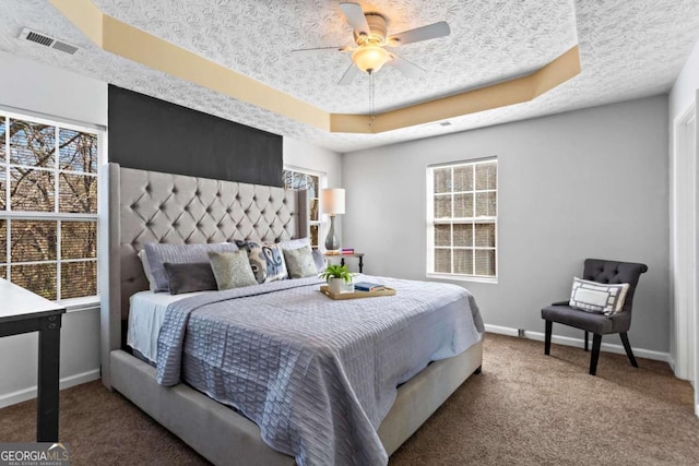 bedroom featuring baseboards, visible vents, a raised ceiling, carpet, and multiple windows