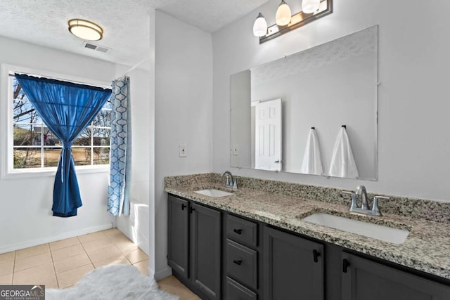 full bathroom with a textured ceiling, tile patterned flooring, a sink, and visible vents