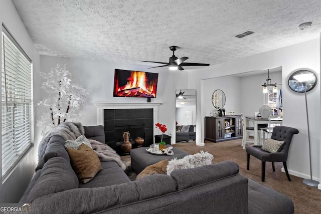 carpeted living room with a ceiling fan, plenty of natural light, visible vents, and a tiled fireplace