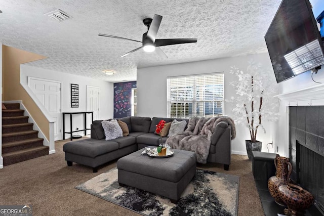 living room with visible vents, a tile fireplace, stairs, a textured ceiling, and carpet floors