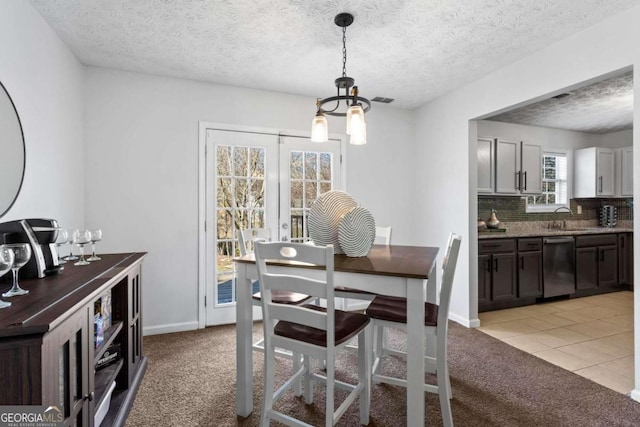 dining area with a textured ceiling, light colored carpet, visible vents, baseboards, and french doors