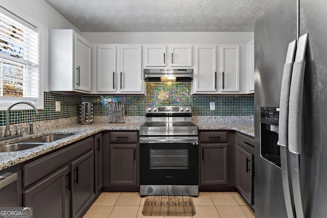 kitchen featuring light tile patterned floors, stainless steel appliances, a sink, range hood, and tasteful backsplash