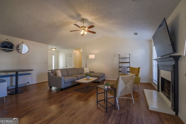 living area with vaulted ceiling, a fireplace, wood finished floors, and visible vents