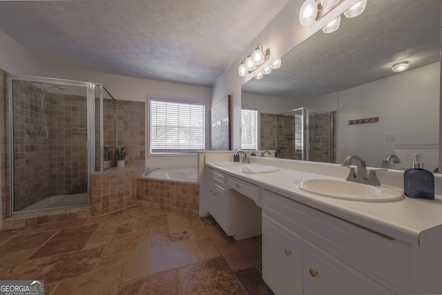 full bath with a stall shower, a sink, a textured ceiling, and a bath