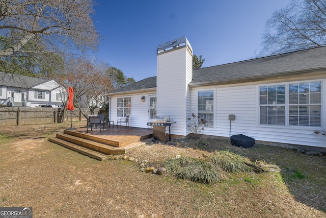 rear view of house with a chimney, fence, and a deck