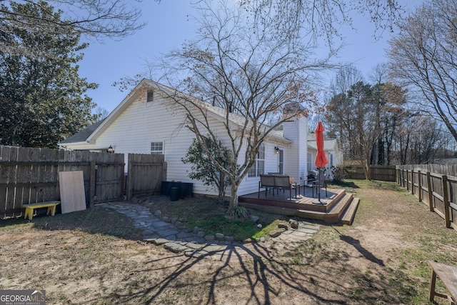 back of house with a fenced backyard, a chimney, and a wooden deck