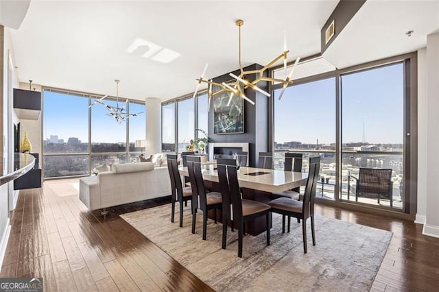 dining space featuring a wealth of natural light, expansive windows, wood-type flooring, and a notable chandelier