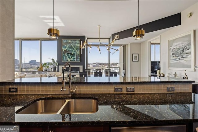 kitchen featuring dark stone countertops, open floor plan, a sink, and decorative backsplash