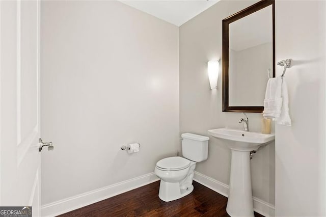 bathroom featuring a sink, toilet, baseboards, and wood finished floors