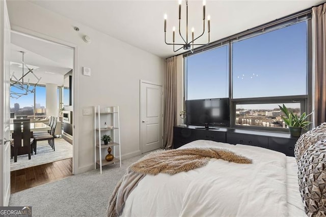 bedroom with carpet flooring, a notable chandelier, baseboards, and wood finished floors