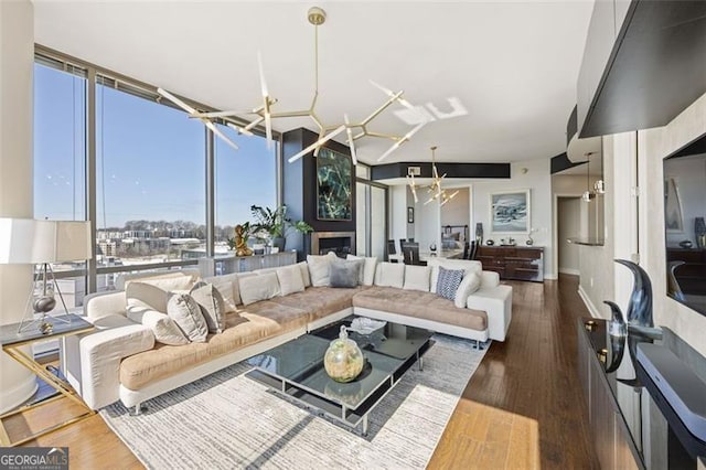 living room featuring an inviting chandelier, expansive windows, and wood finished floors