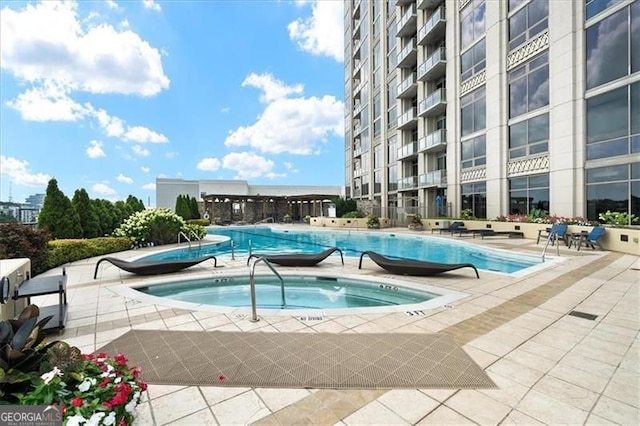 community pool with a community hot tub and a patio area