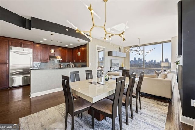 dining room featuring an inviting chandelier, baseboards, dark wood finished floors, and a city view