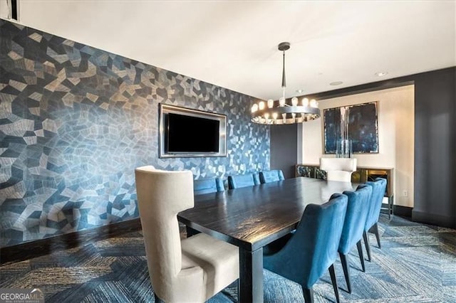 dining space featuring a chandelier, an accent wall, baseboards, and wallpapered walls