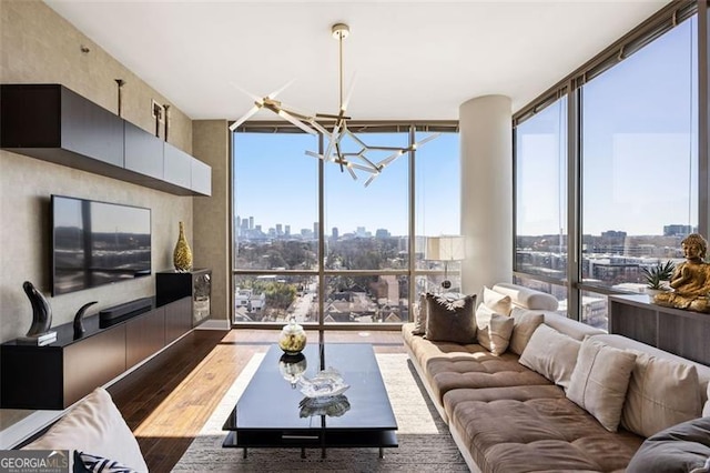 living room featuring a wealth of natural light, expansive windows, a chandelier, and wood finished floors