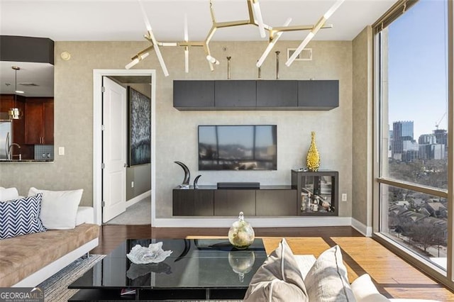 living room featuring baseboards, wood finished floors, visible vents, and floor to ceiling windows