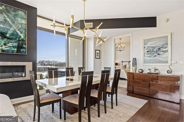 dining area featuring an inviting chandelier, baseboards, visible vents, and wood finished floors