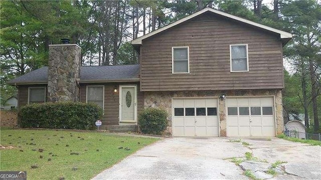 split level home with driveway, a garage, and a front lawn