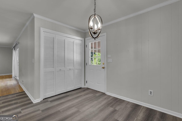 entrance foyer with a chandelier, ornamental molding, dark wood-type flooring, and baseboards