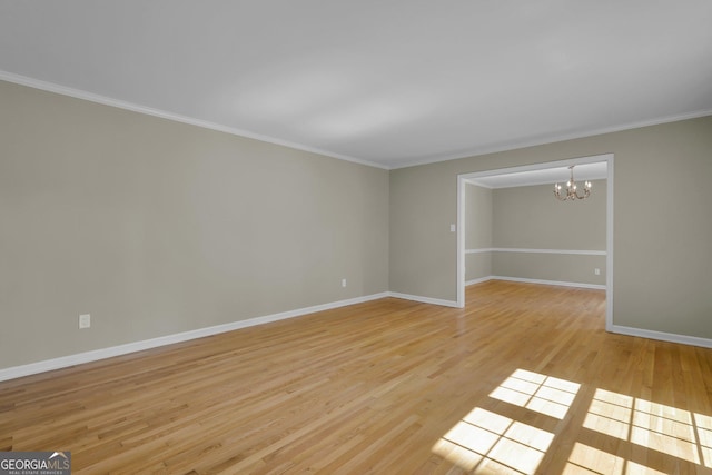 spare room featuring baseboards, crown molding, light wood-style flooring, and a notable chandelier