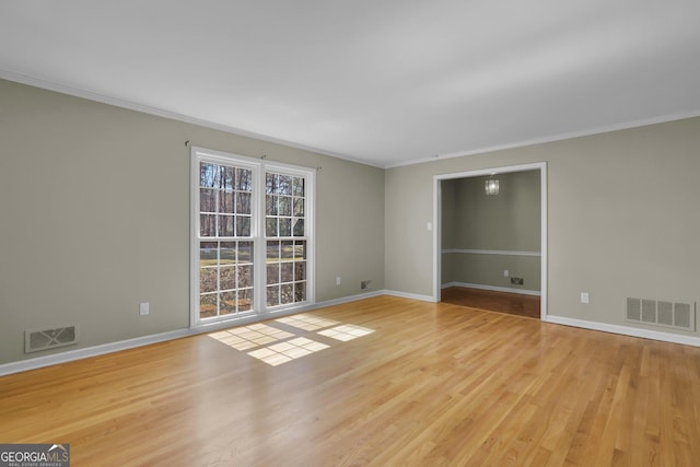 empty room featuring wood finished floors, visible vents, and baseboards